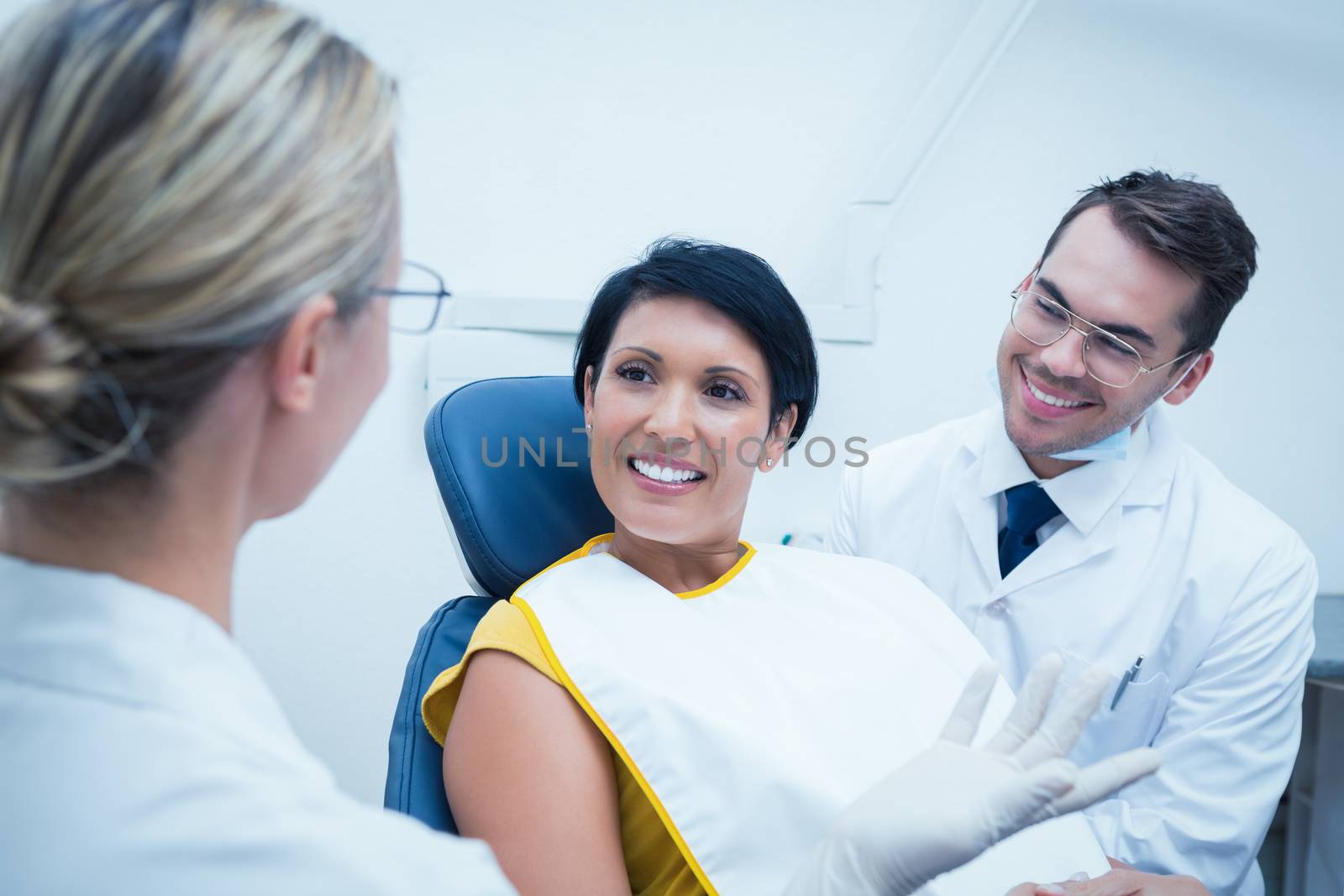 Smiling dentist and assistant with female patient by Wavebreakmedia