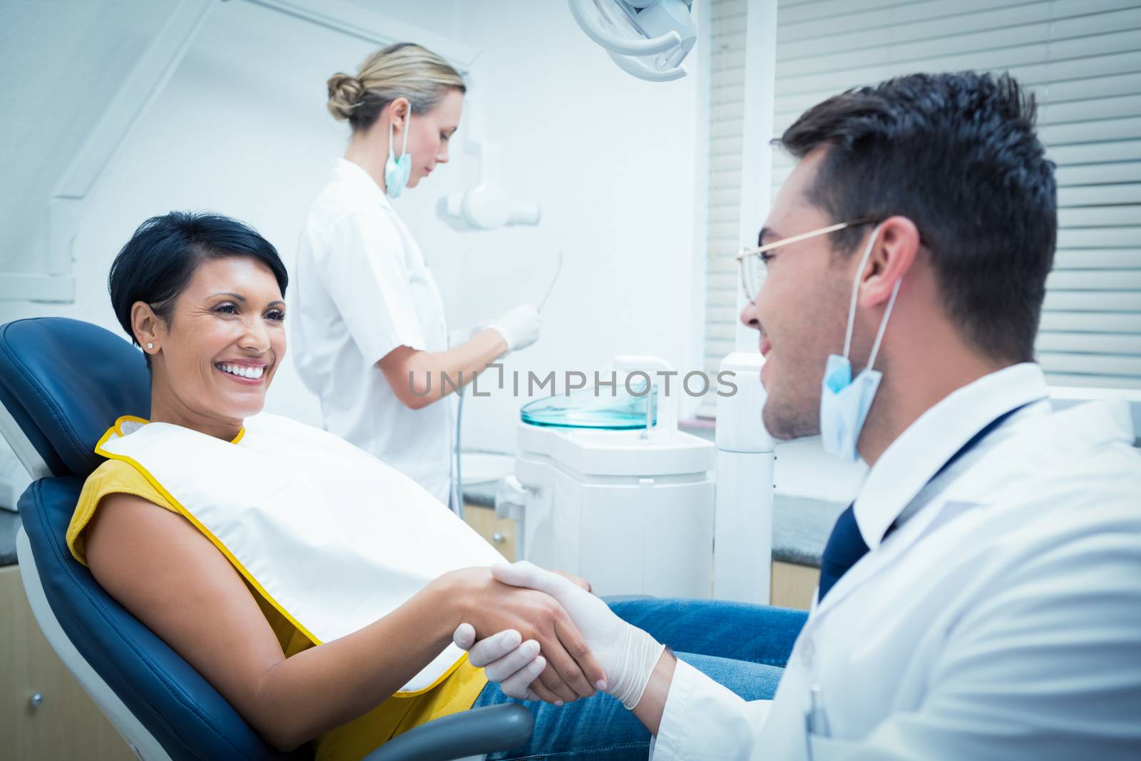 Male dentist shaking hands with woman by Wavebreakmedia