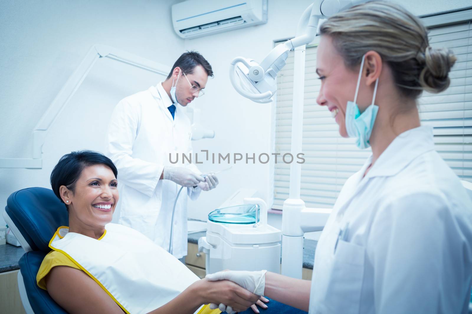 Female dentist shaking hands with woman by Wavebreakmedia