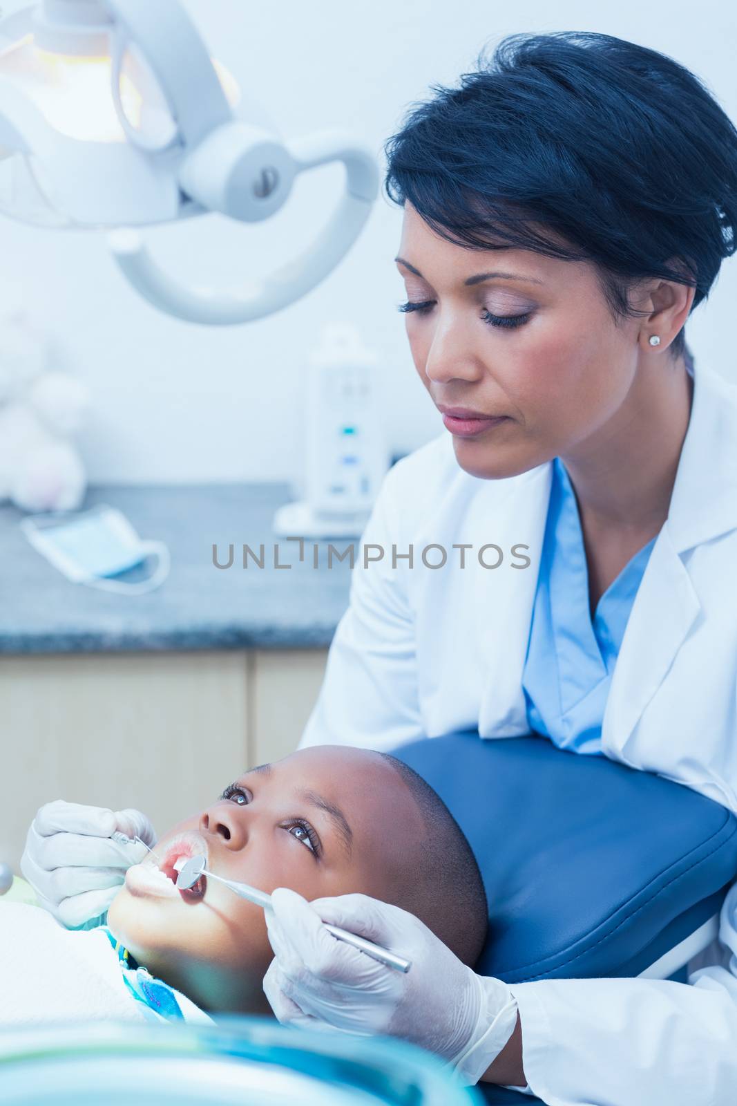 Female dentist examining boys teeth in the dentists chair