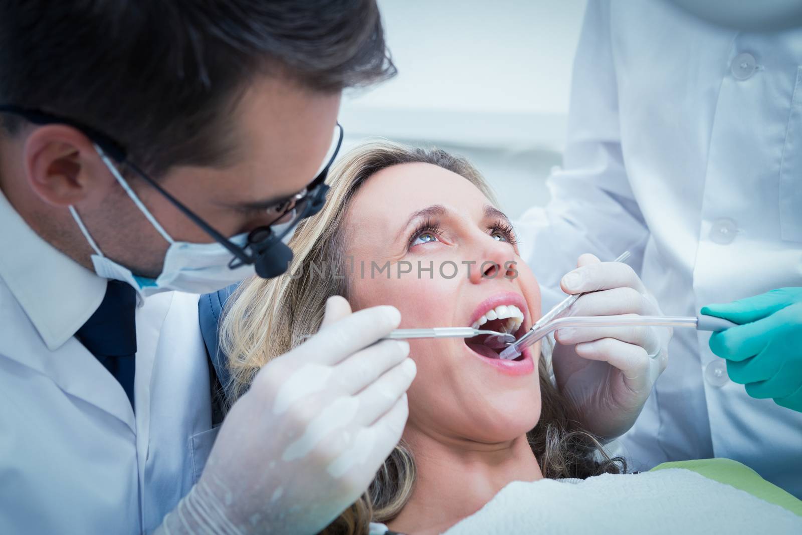 Close up of woman having her teeth examined by dentist and assistant