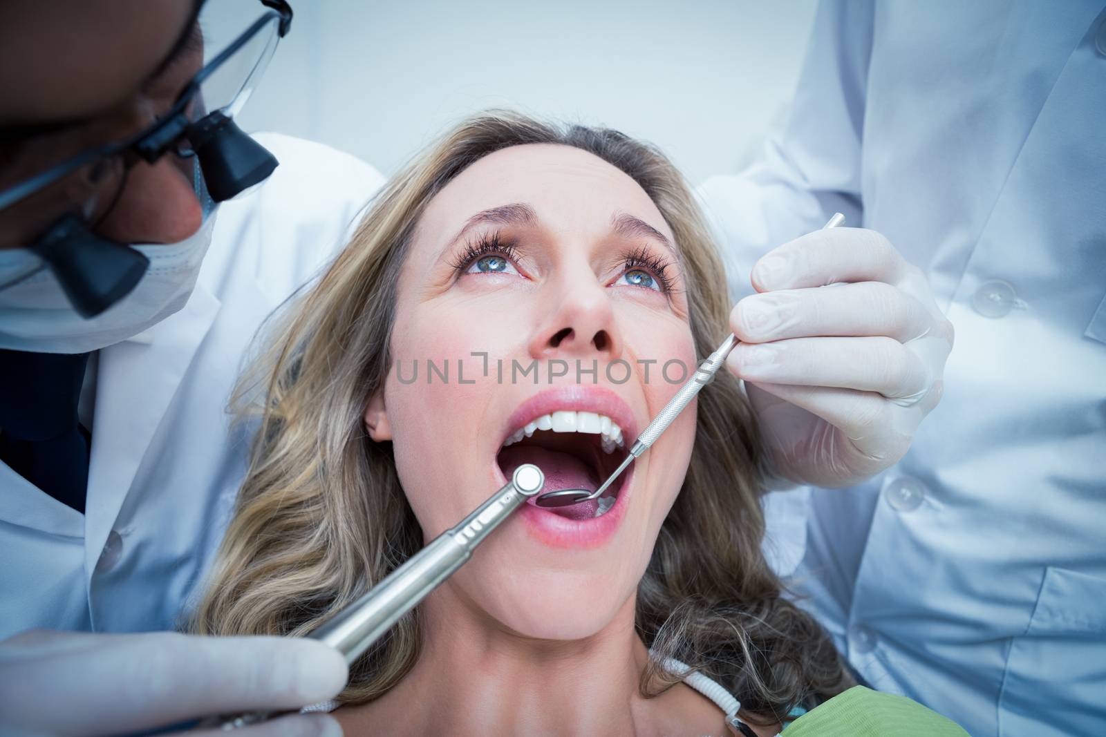 Close up of woman having her teeth examined by dentist and assistant