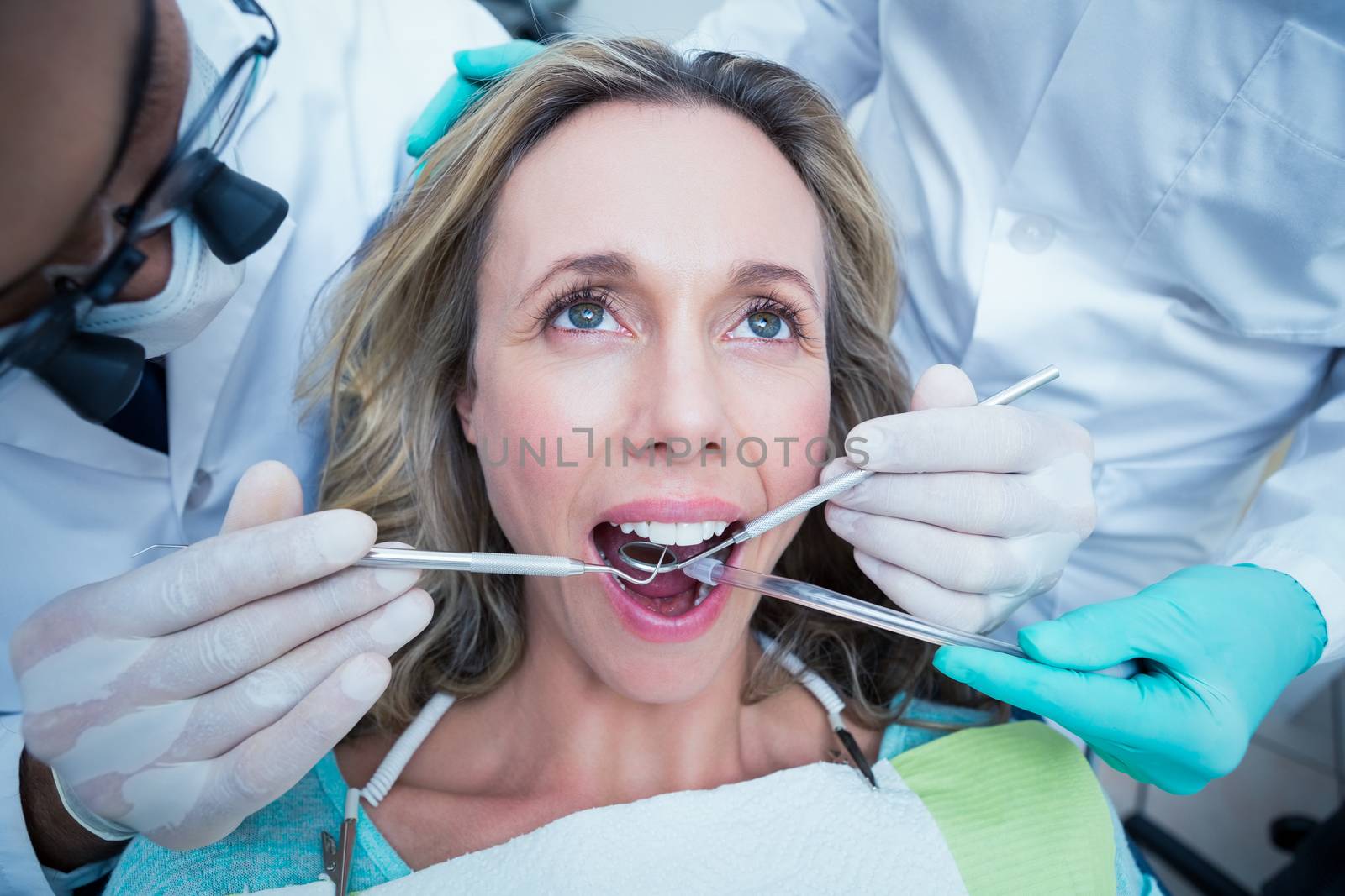 Close up of woman having her teeth examined by dentist and assistant