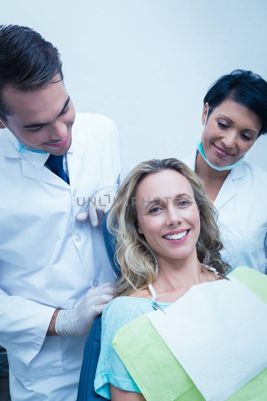 Portrait of happy male dentist with assistant and female patient