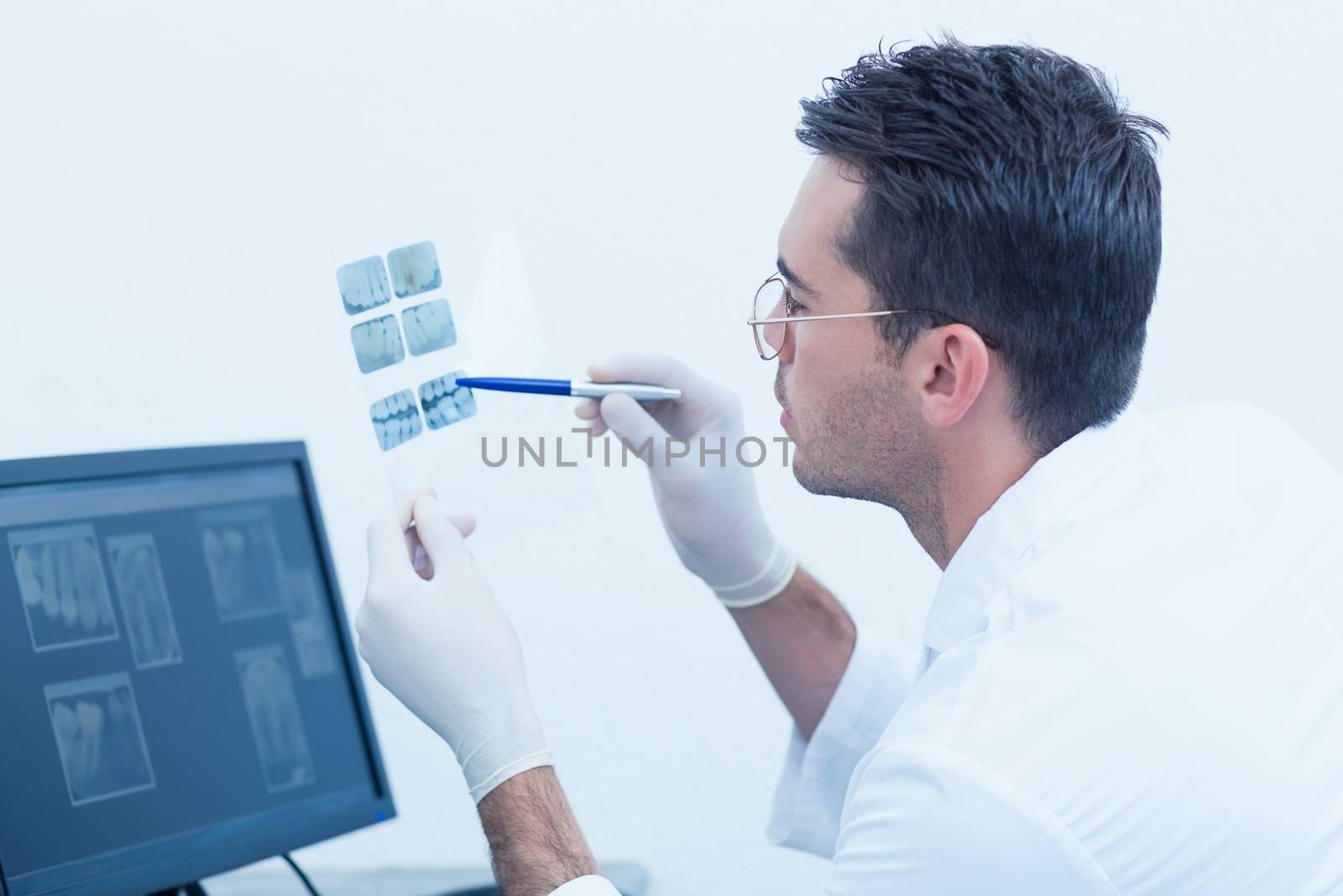 Side view of concentrated male dentist looking at x-ray