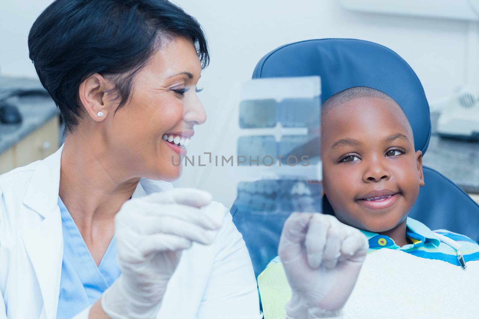 Female dentist showing boy his mouth x-ray by Wavebreakmedia