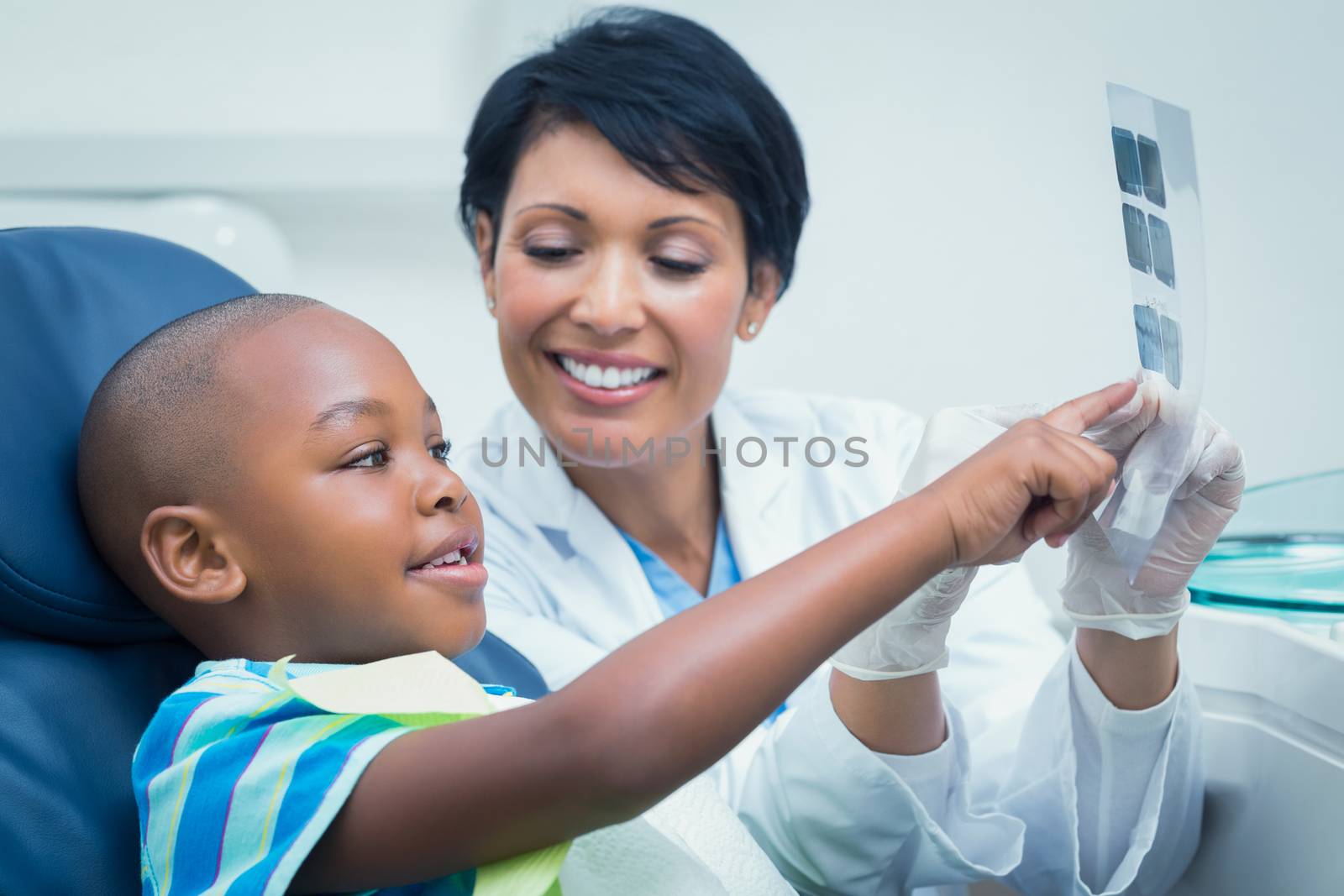 Female dentist showing young boy his mouth x-ray in the dentists chair