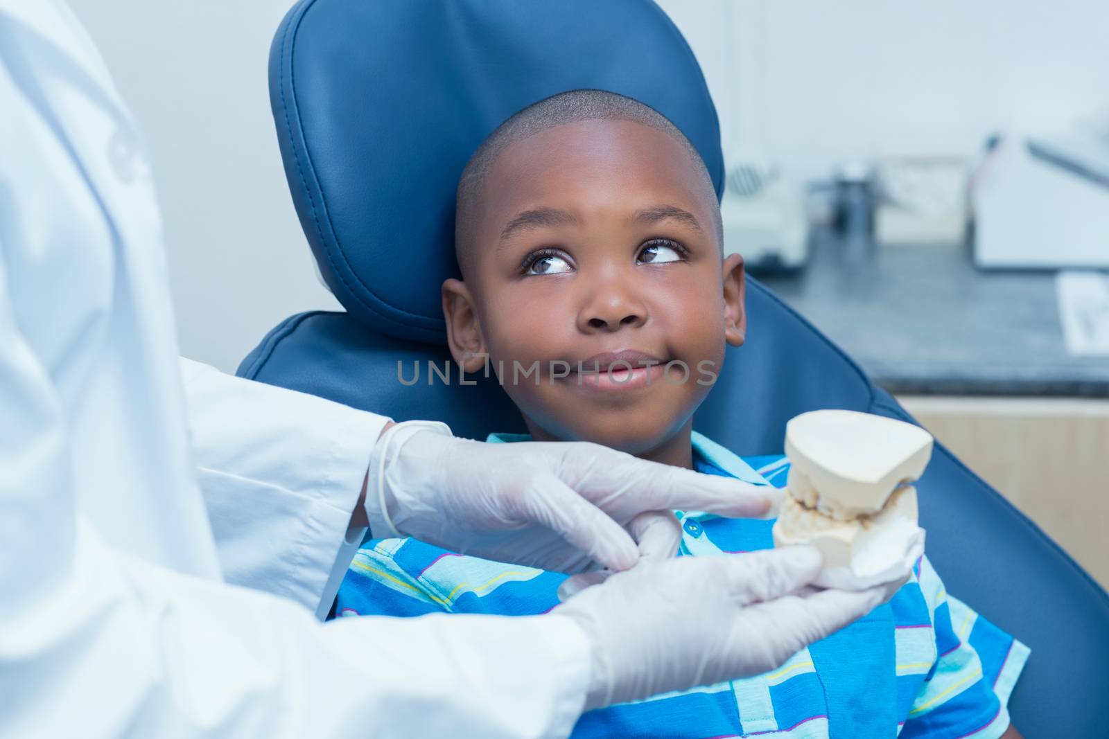 Cropped dentist showing young boy prosthesis teeth in the dentists chair