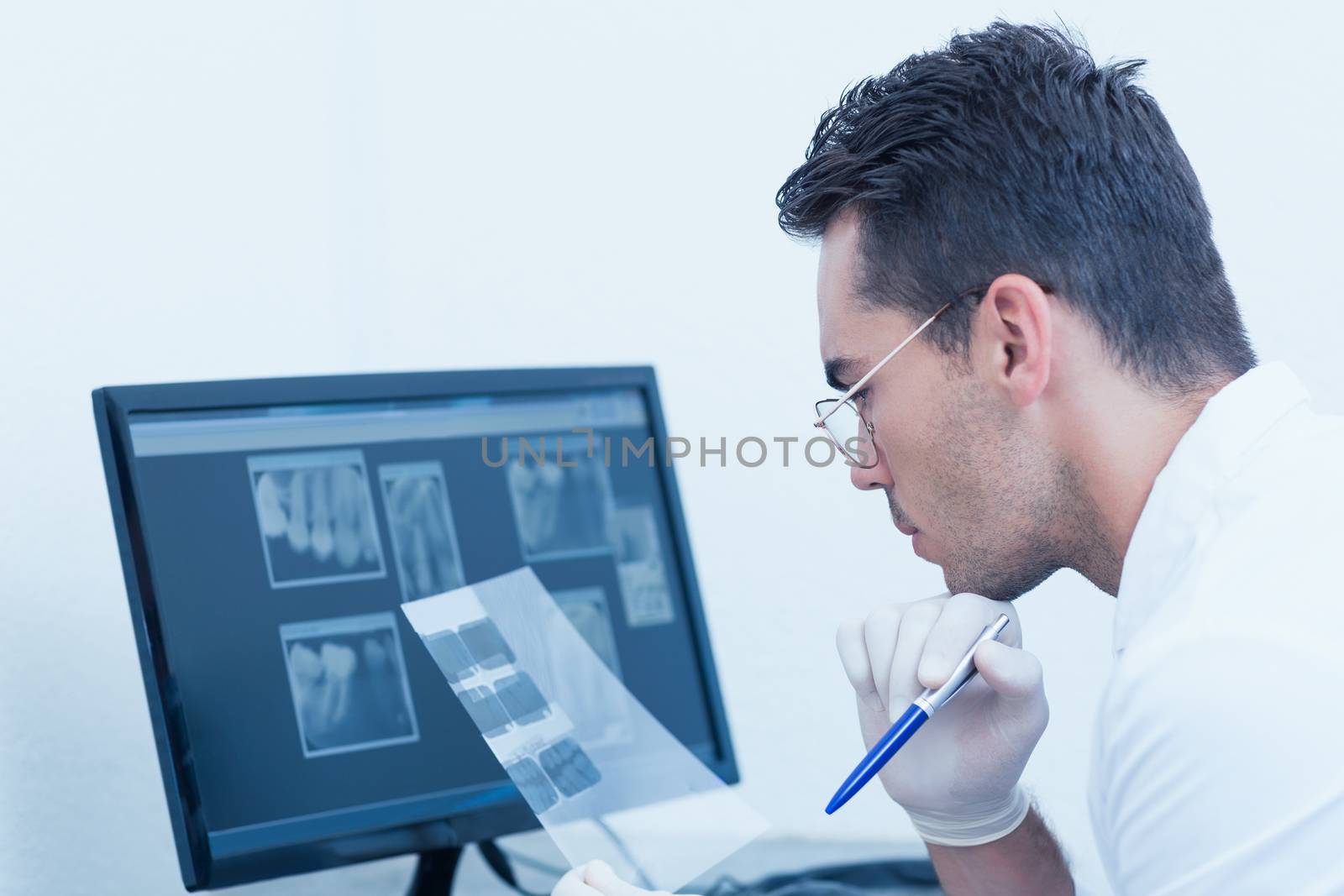 Concentrated male dentist looking at x-ray