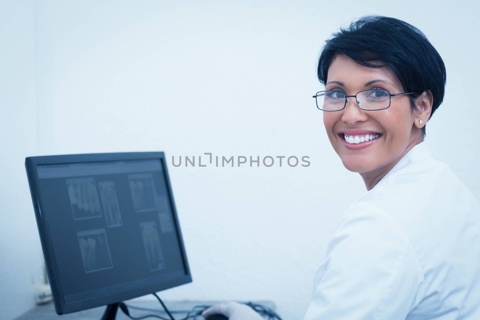 Smiling female dentist with x-ray on computer by Wavebreakmedia