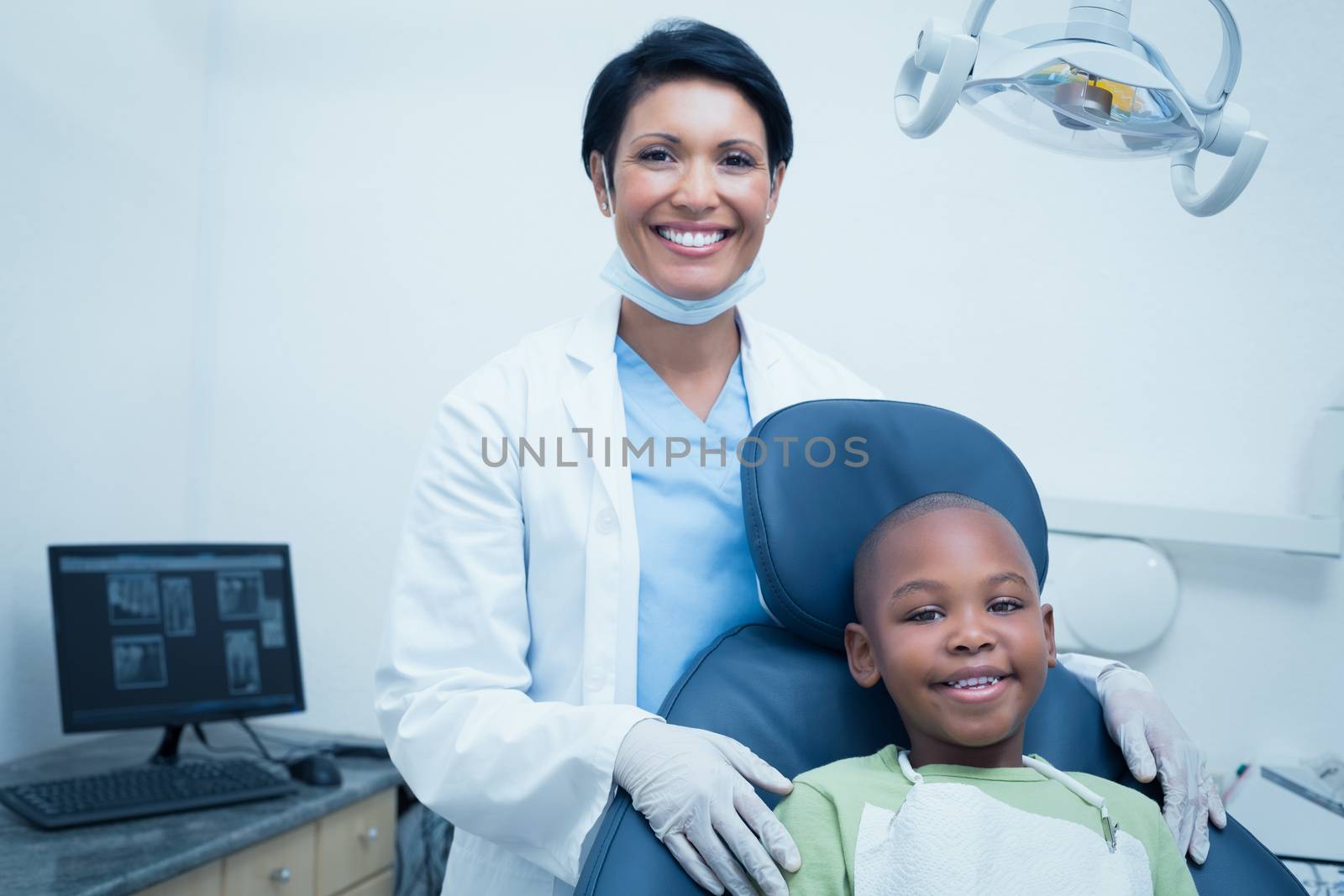 Portrait of female dentist examining boys teeth in the dentists chair