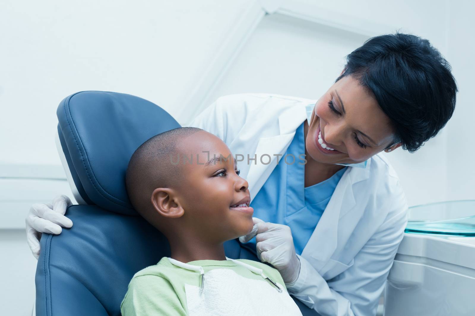 Female dentist examining boys teeth in the dentists chair