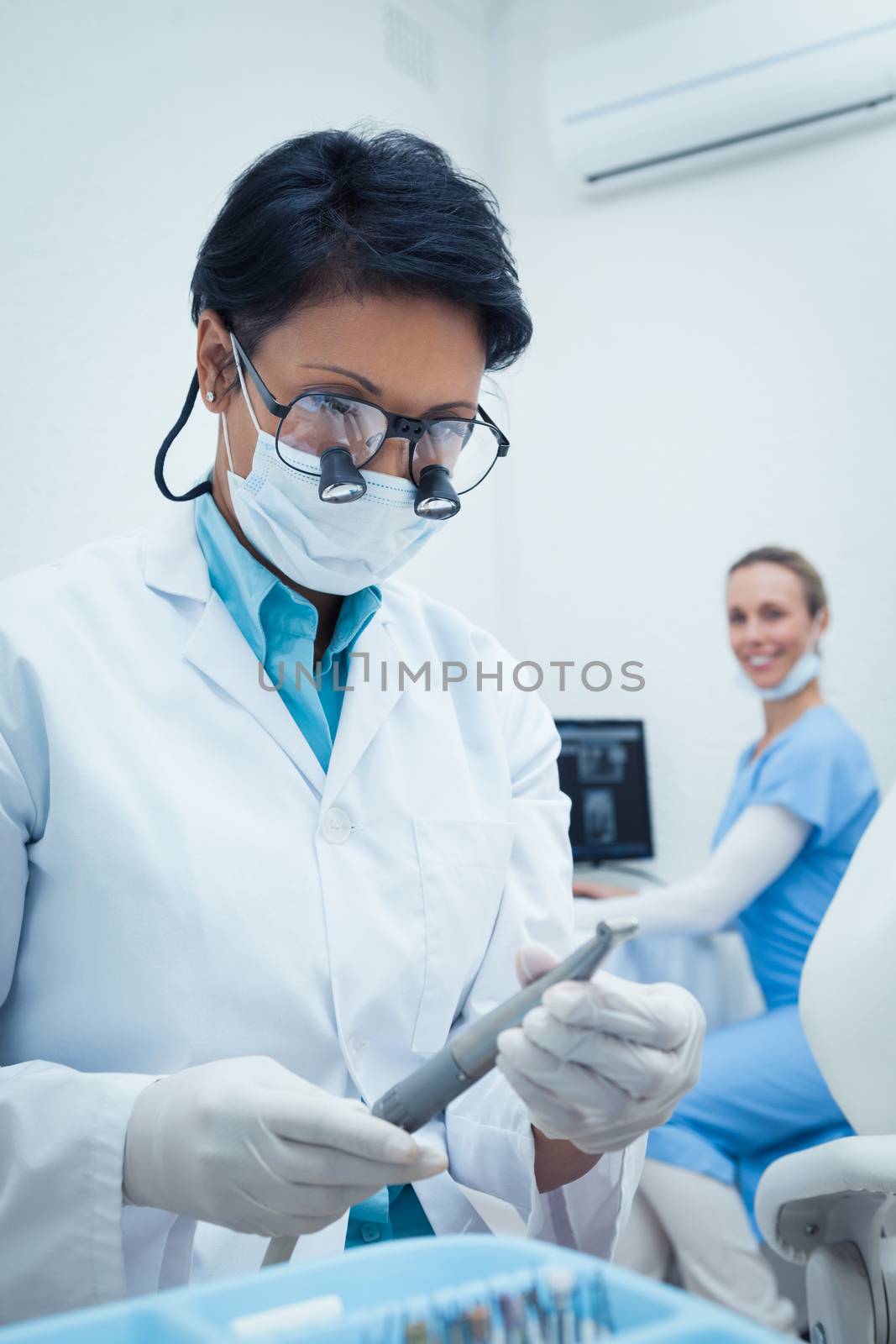 Concentrated dentist looking at dental tool by Wavebreakmedia
