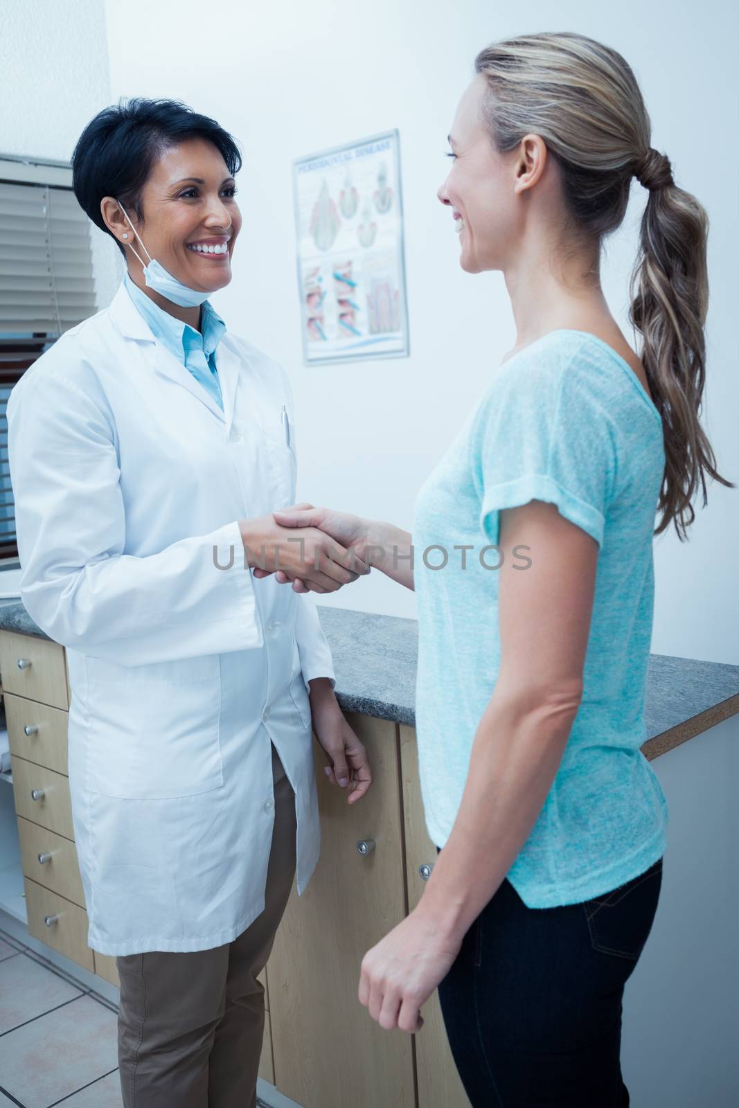 Side view of female dentist shaking hands with woman