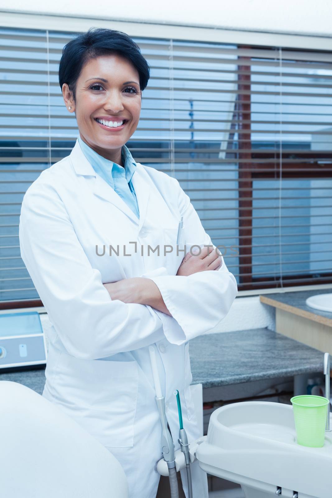 Portrait of smiling female dentist standing with arms crossed