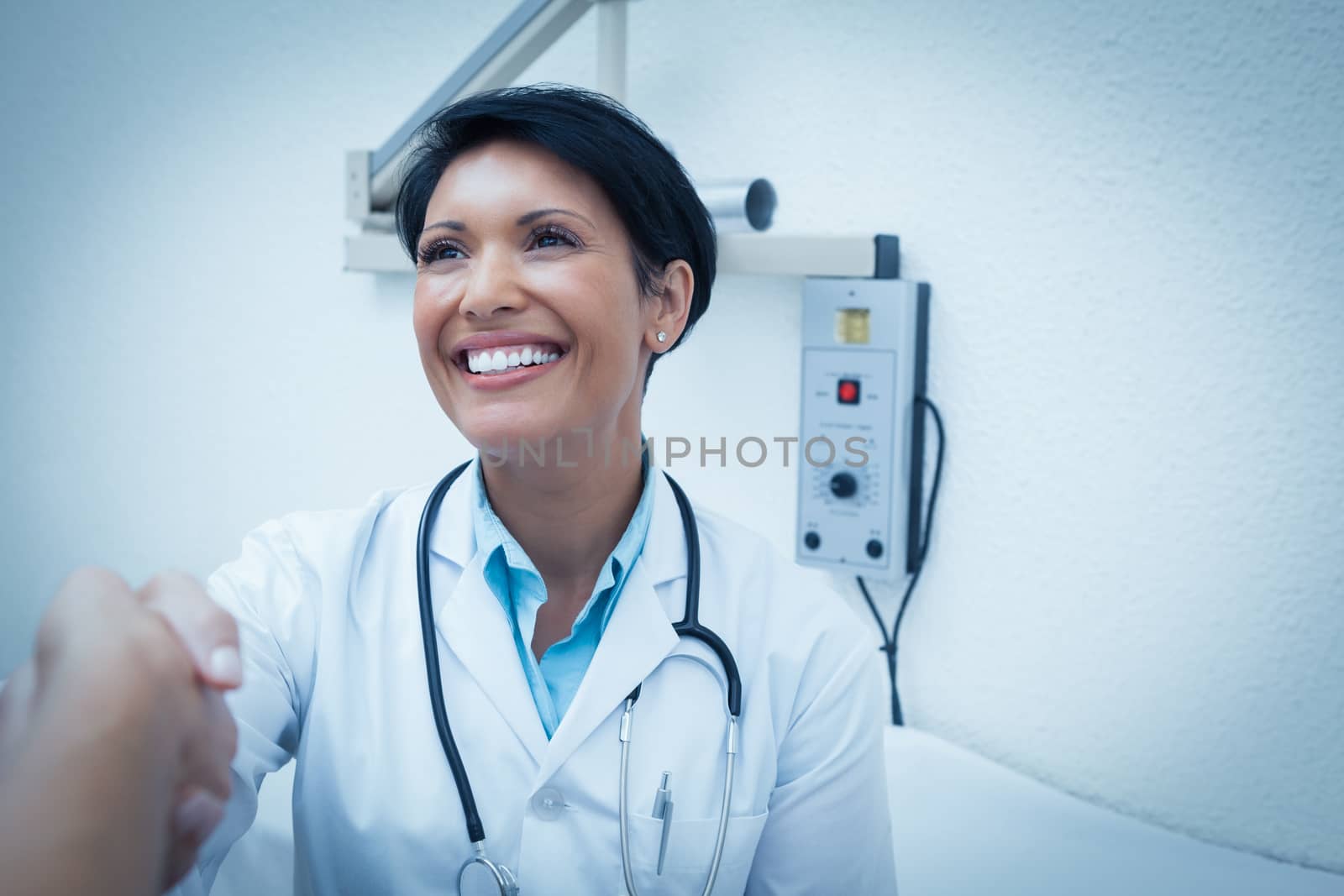 Cheerful female dentist shaking hands with cropped patient