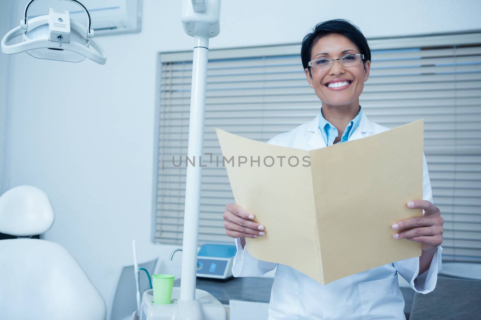 Portrait of smiling female dentist reading reports