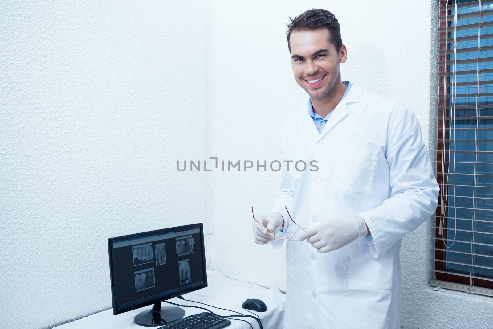 Portrait of smiling male dentist with computer monitor