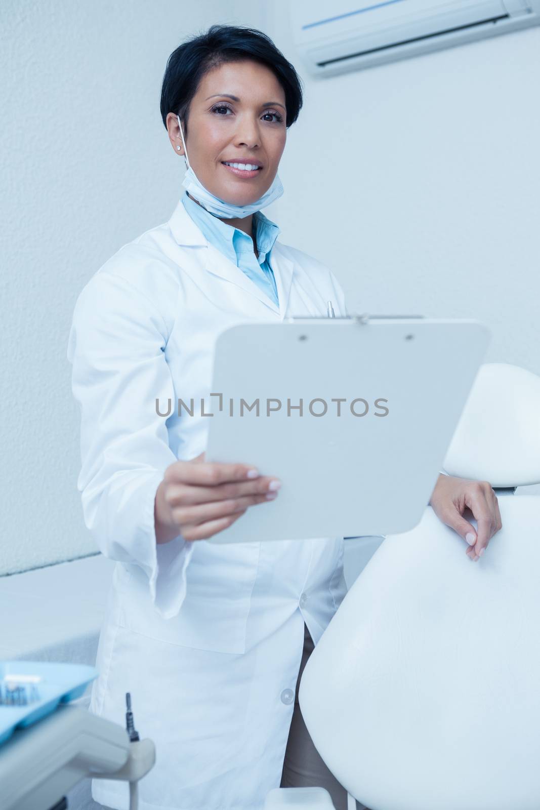 Portrait of smiling young female dentist holding clipboard