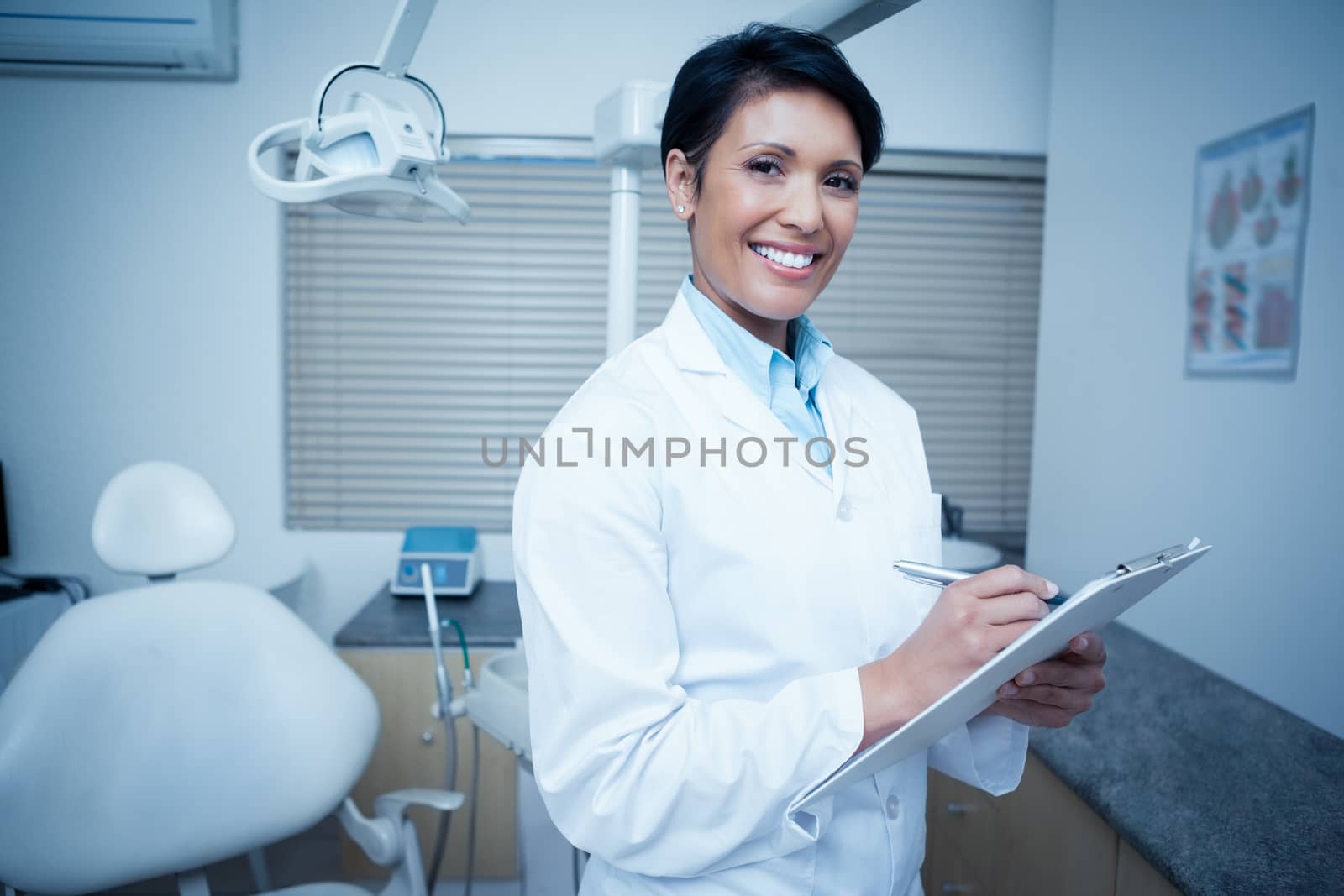 Portrait of smiling young female dentist holding clipboard