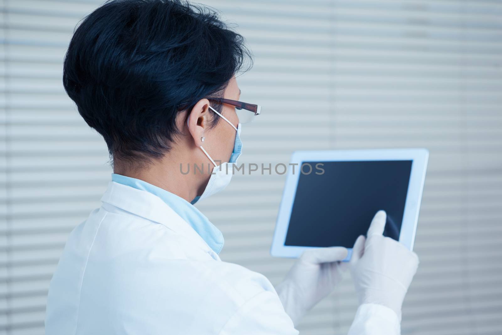Rear view of female dentist using digital tablet