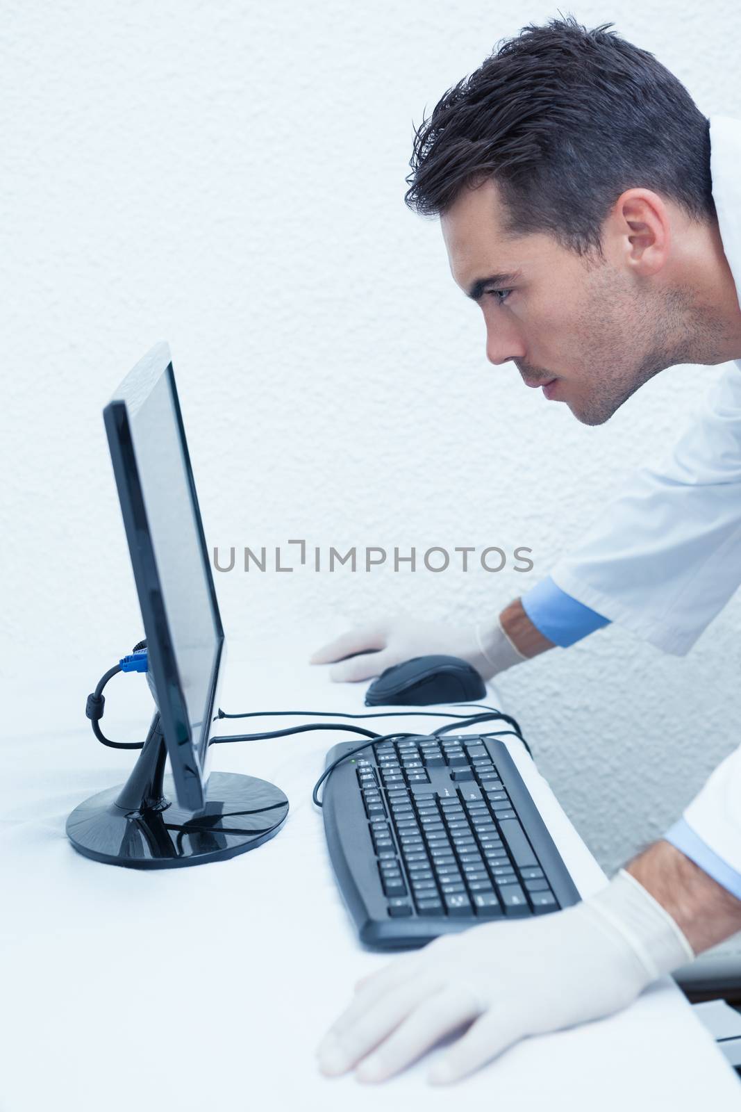 Concentrated male dentist looking at computer monitor by Wavebreakmedia