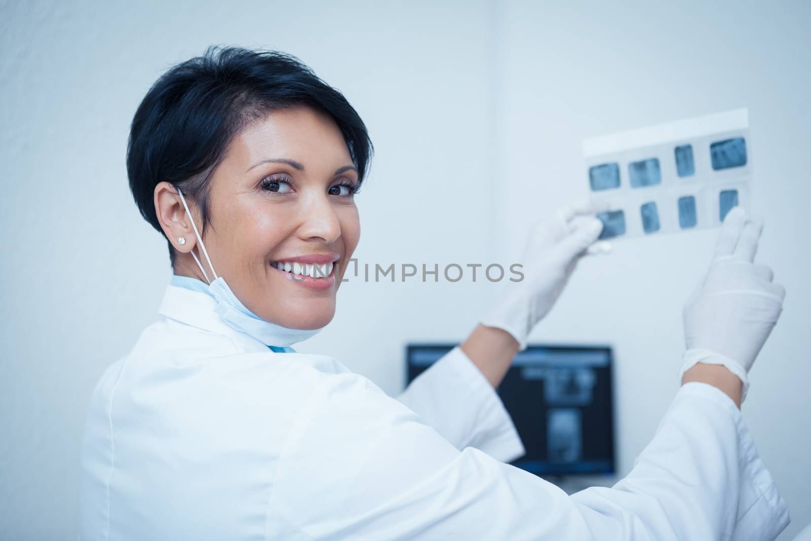 Smiling female dentist holding x-ray by Wavebreakmedia
