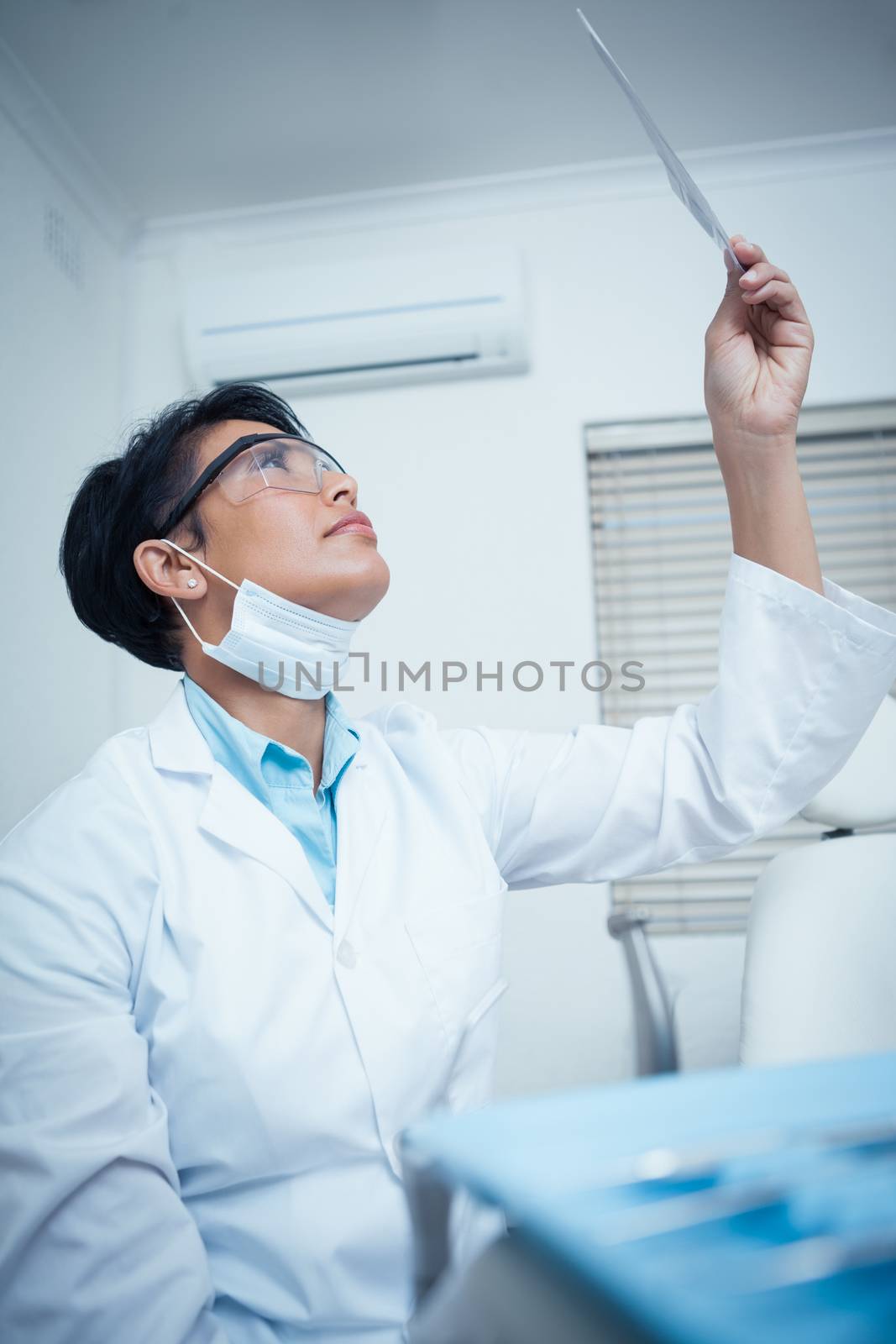 Low angle view of concentrated young female dentist looking at x-ray
