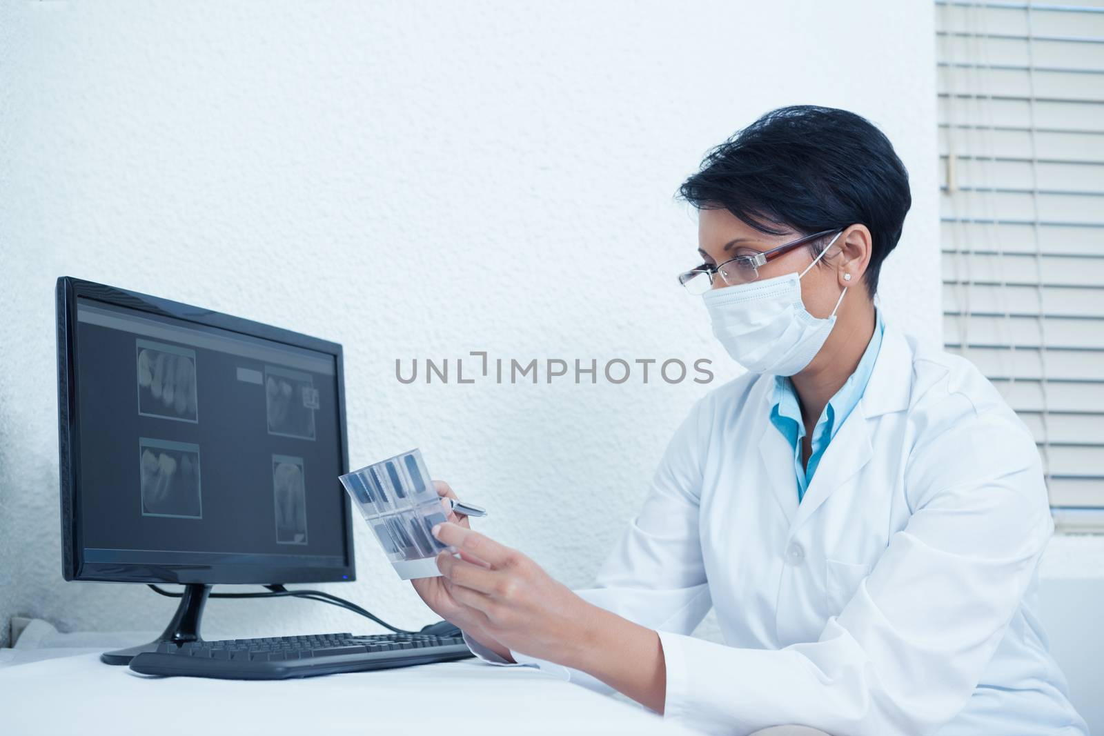 Concentrated female dentist looking at x-ray by computer