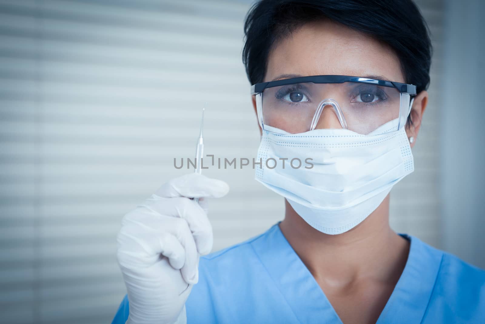 Dentist in surgical mask holding dental tool by Wavebreakmedia