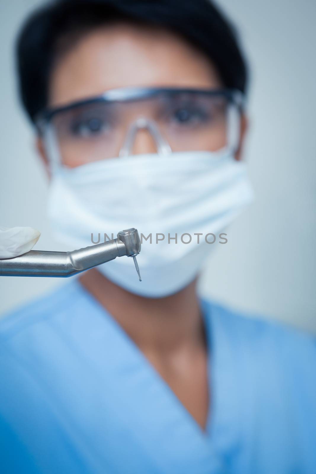 Dentist in surgical mask holding dental drill by Wavebreakmedia