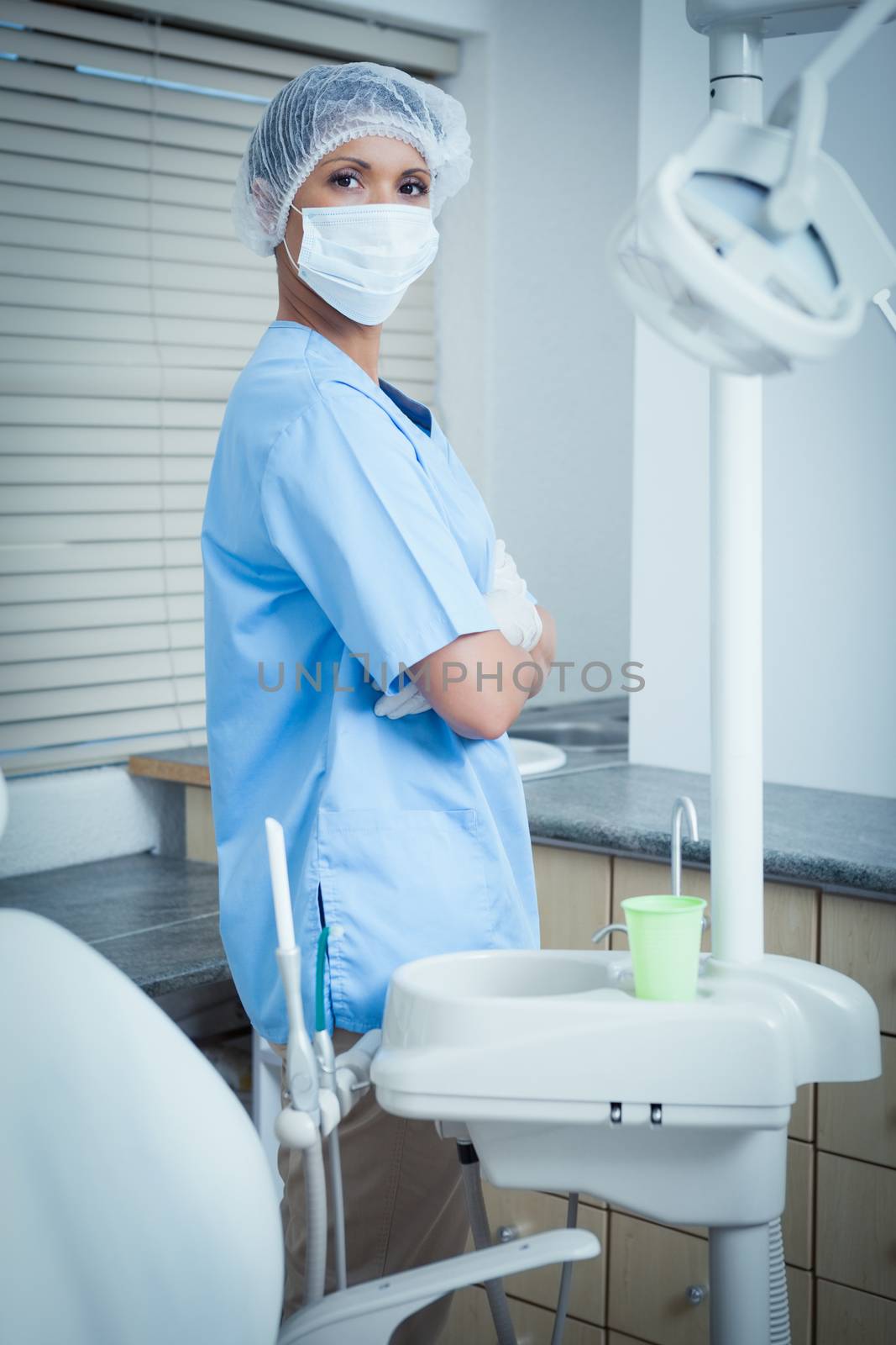 Dentist wearing surgical mask with arms crossed by Wavebreakmedia