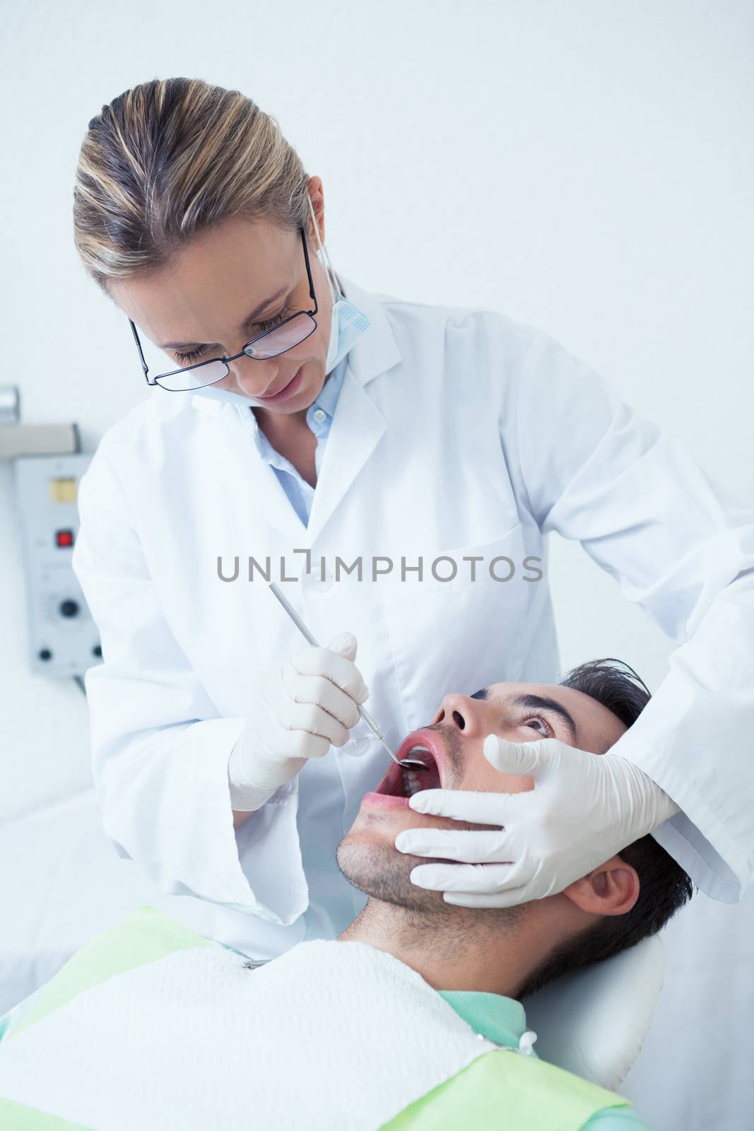 Female dentist examining mans teeth in the dentists chair