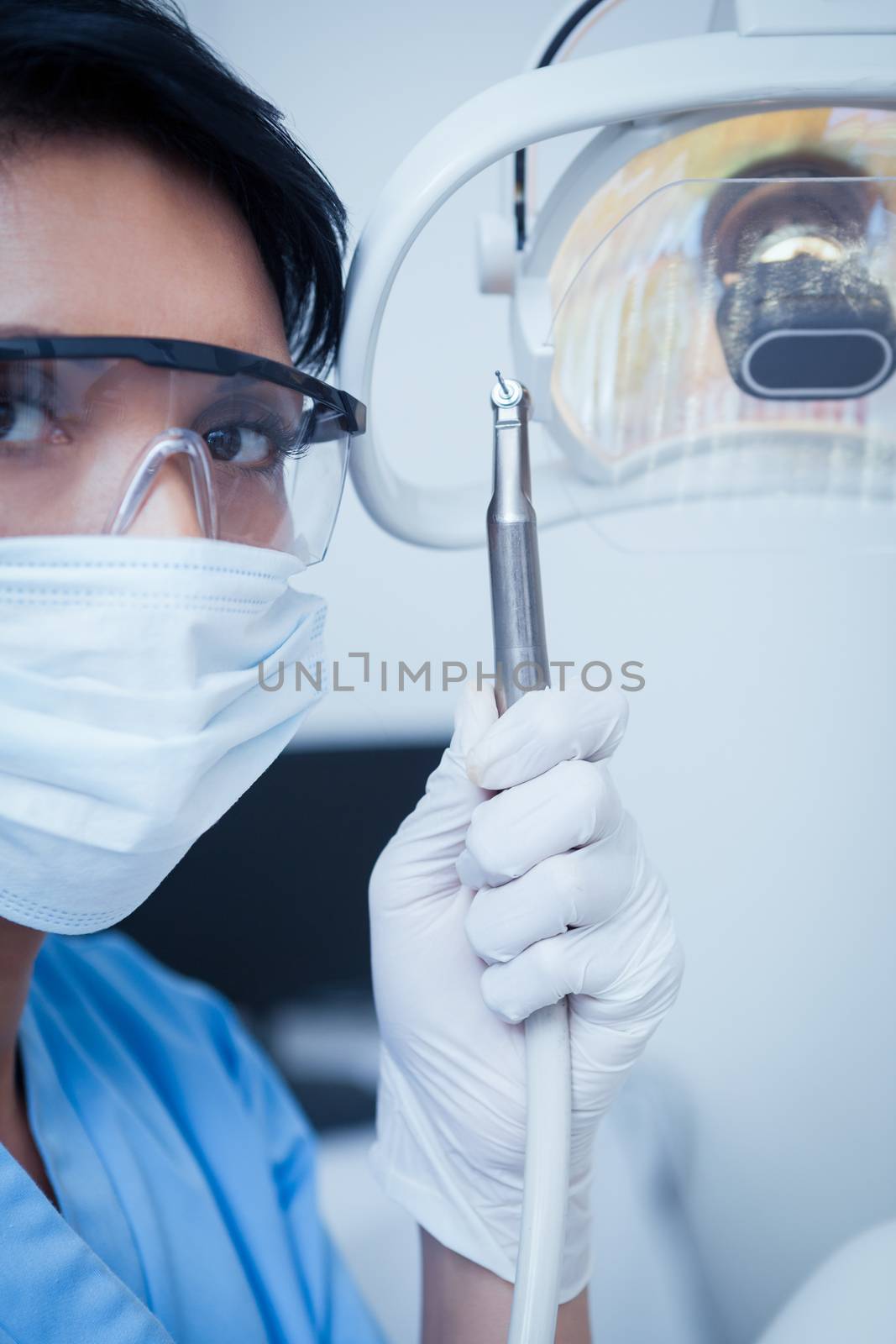 Portrait of female dentist in surgical mask holding dental drill