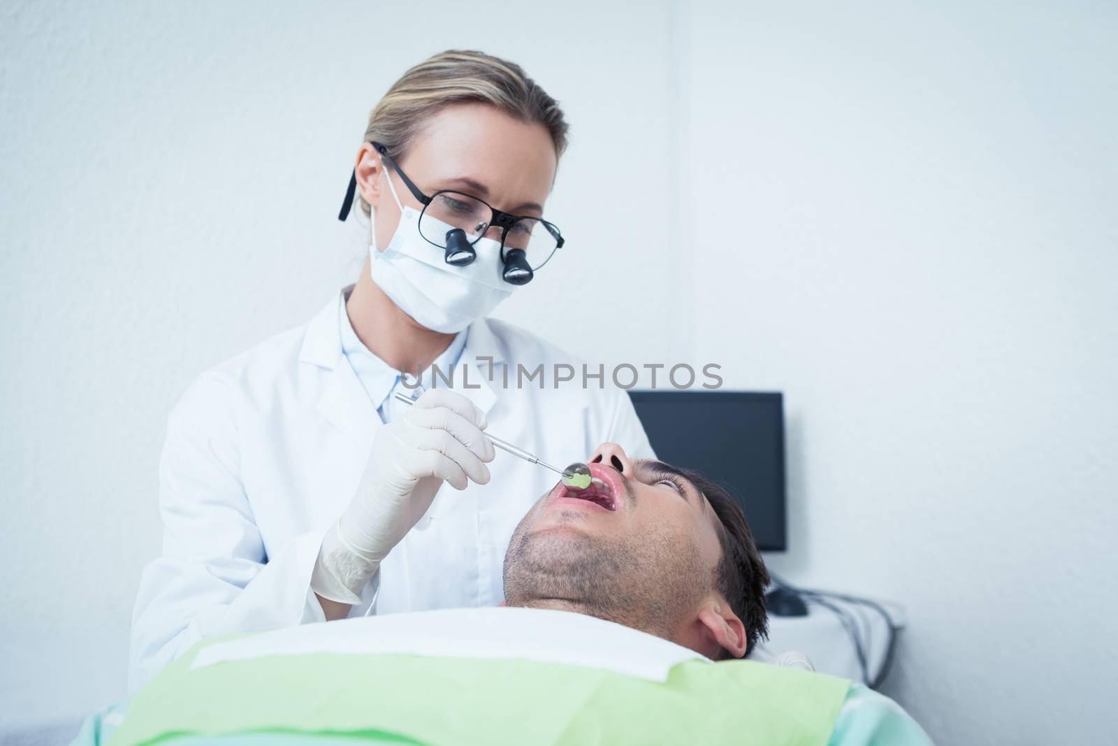 Female dentist examining mans teeth in the dentists chair