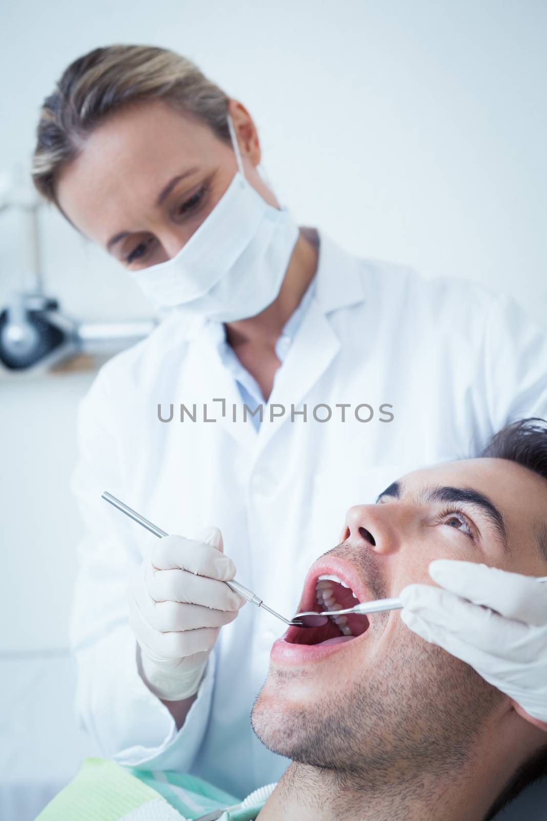 Female dentist examining mans teeth in the dentists chair