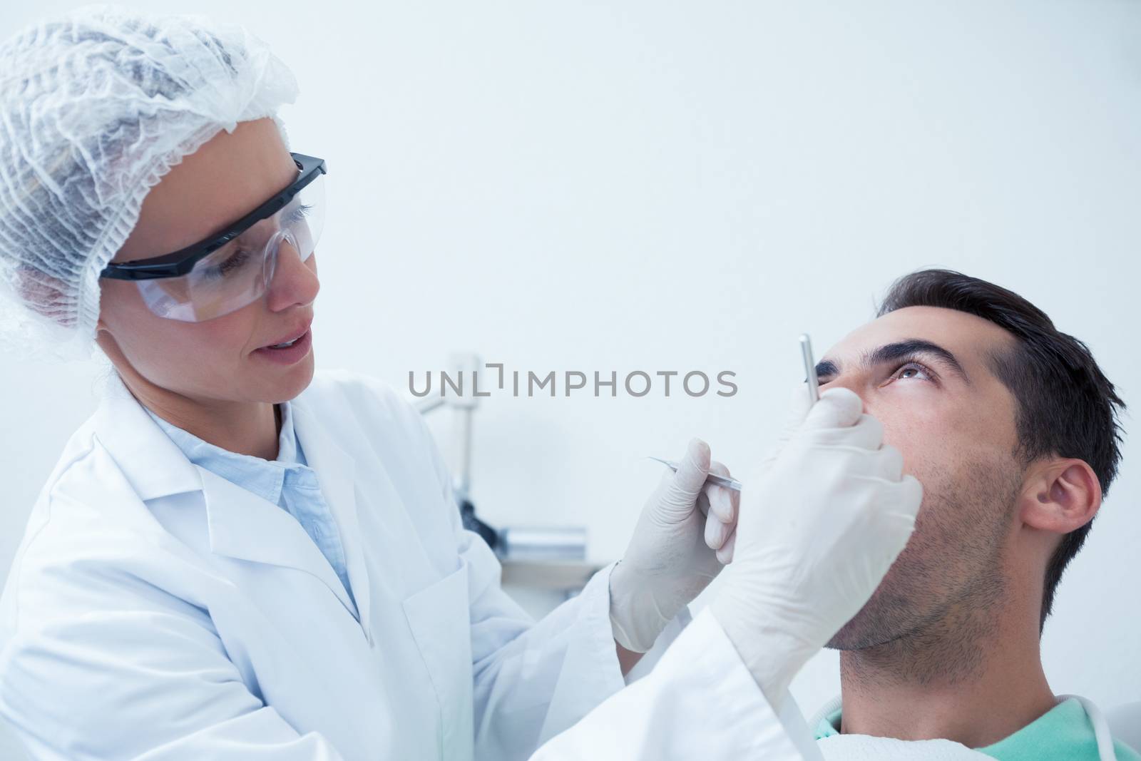 Female dentist examining mans teeth in the dentists chair