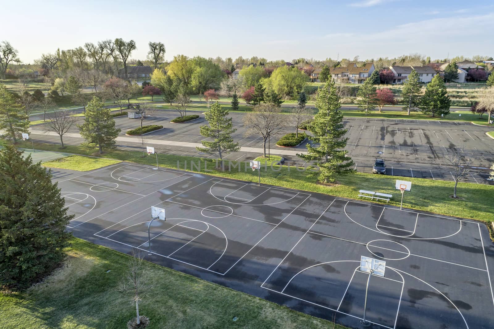 aerial view of a public park with recreational basketball court, sunrise light with long shadows at springtime