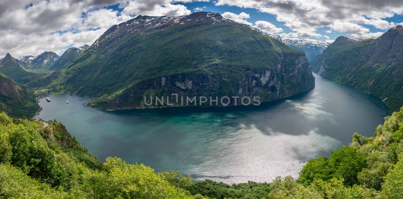 Panorama of the whole Geirangerfjord, a UNESCO heritage site, and the village of Geiranger and some mountains in Møre og Romsdal, Norway, seen from the Eagle Bend (Ørnesvingen) viewpoint at Eagle Road (Ørnevegen).
