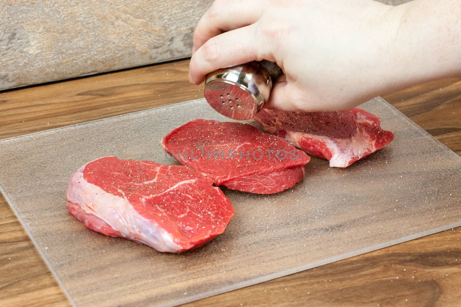 Seasoning fresh steaks with salt a pepper before cooking