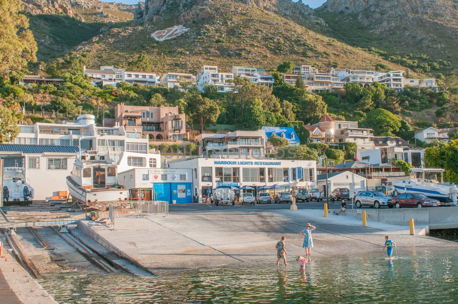 CAPE TOWN, SOUTH AFRICA - DECEMBER 11, 2014:  Unidentified children playing in the water at the harbor in Gordons Bay at sunset