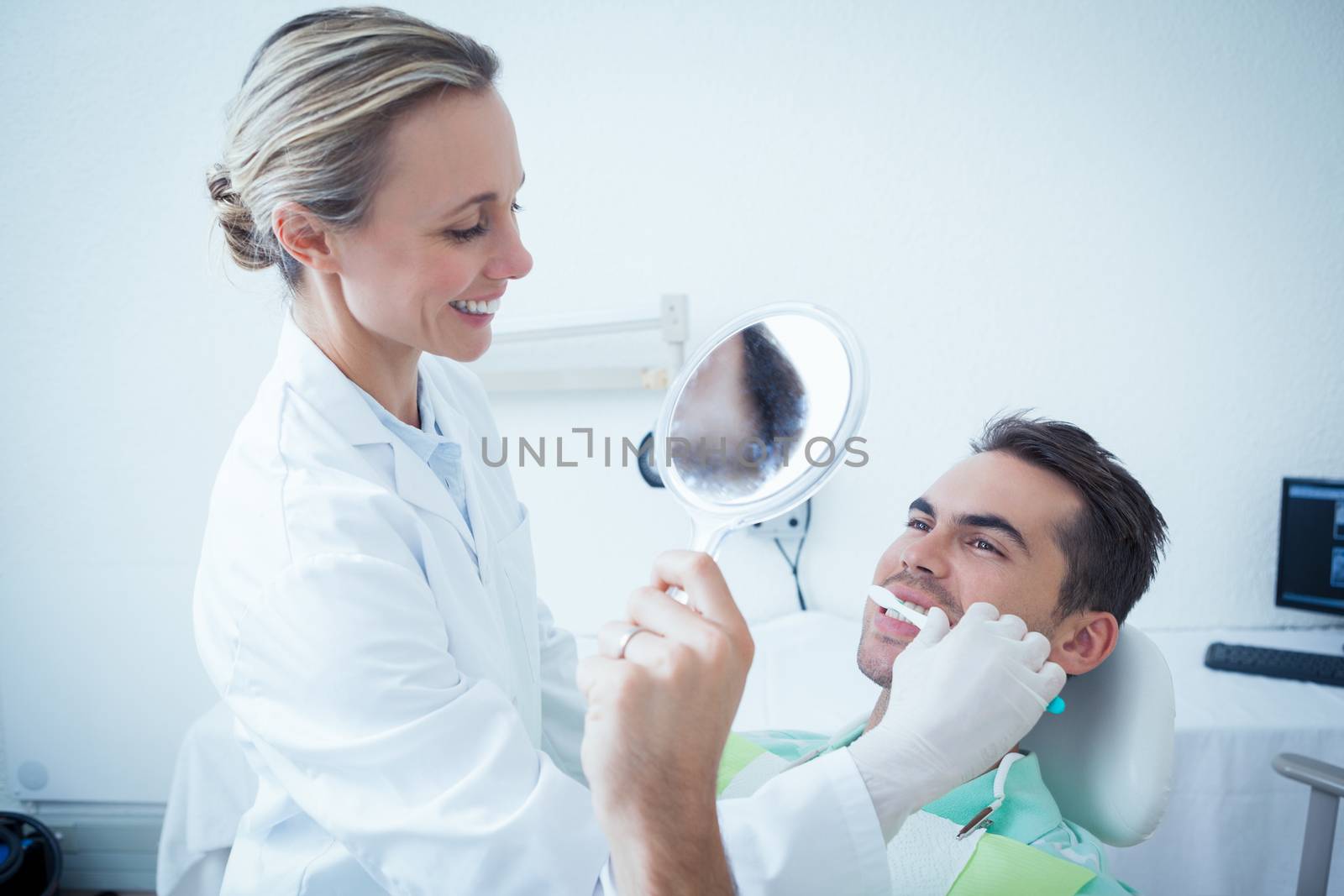 Female dentist brushing mans teeth by Wavebreakmedia