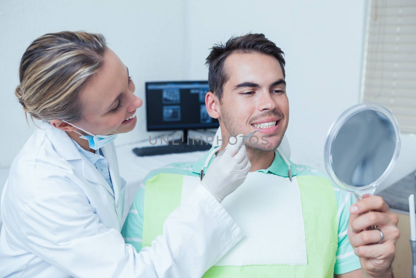 Female dentist examining mans teeth in the dentists chair