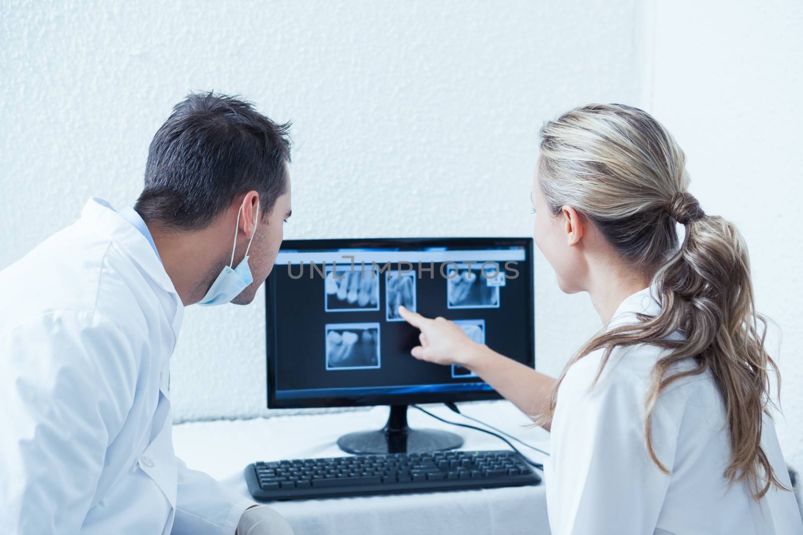 Two concentrated dentists looking at x-ray on computer