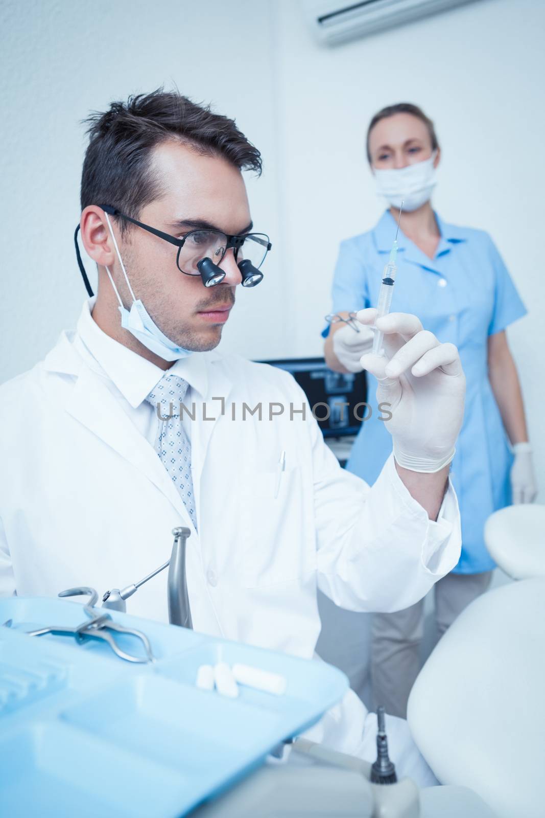 Concentrated male dentist looking at injection