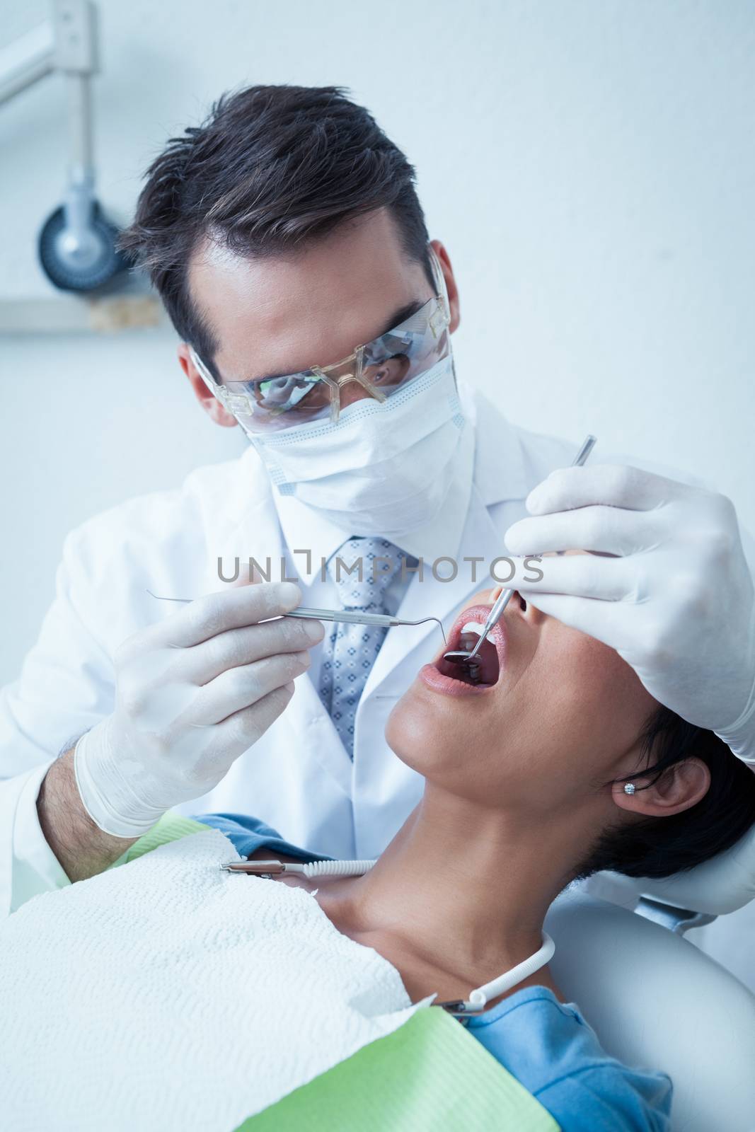 Male dentist examining womans teeth in the dentists chair