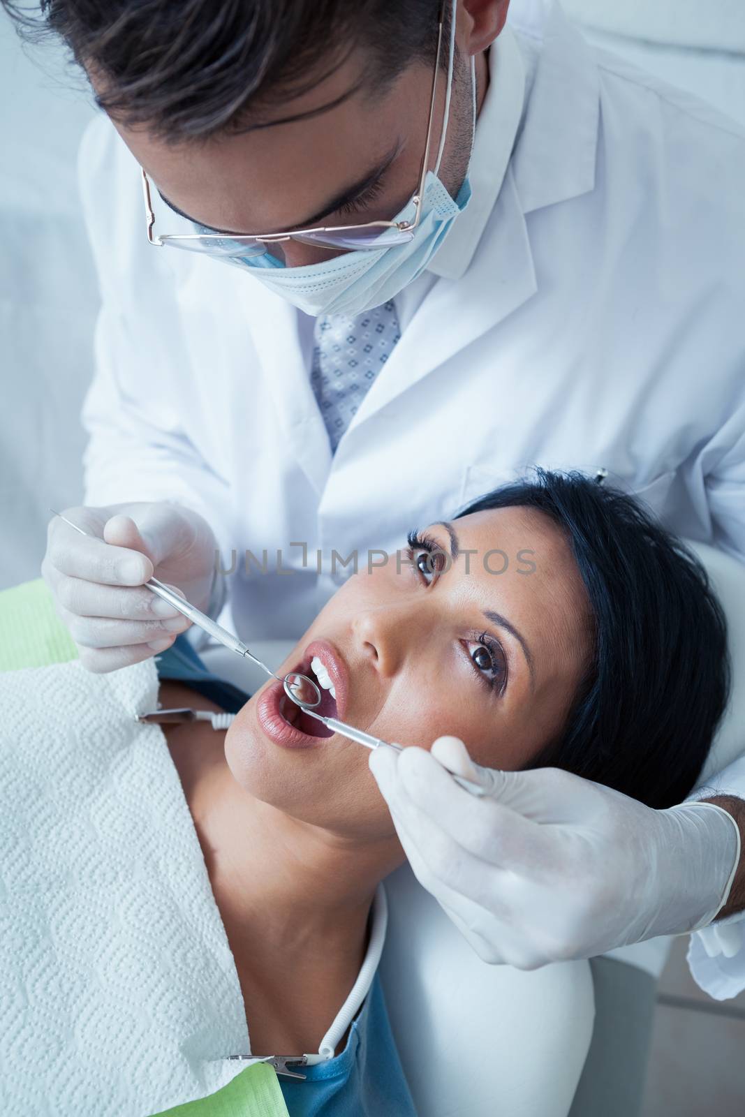 Male dentist examining womans teeth in the dentists chair