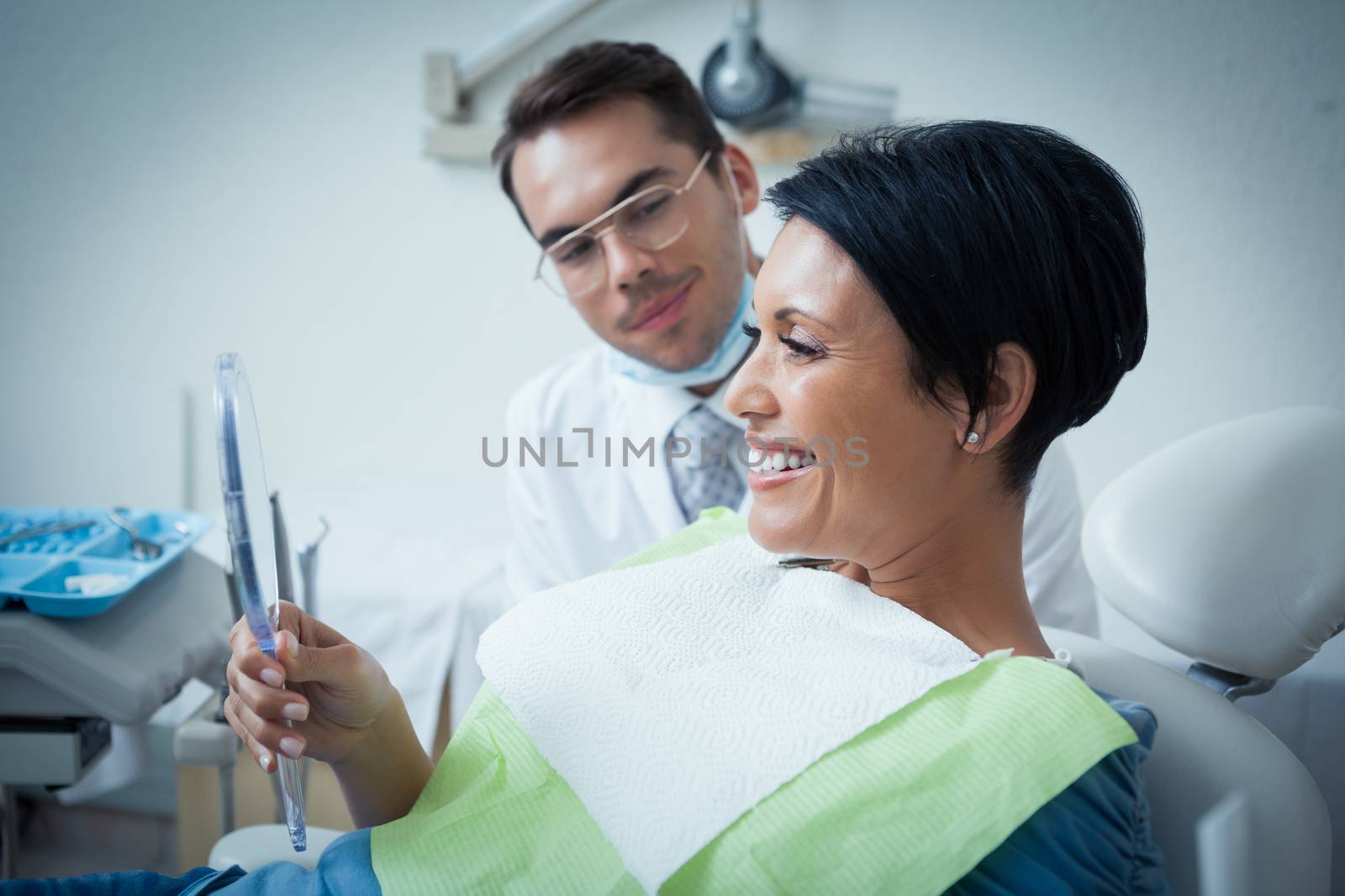 Side view of smiling female patient with dentist in the dentists chair