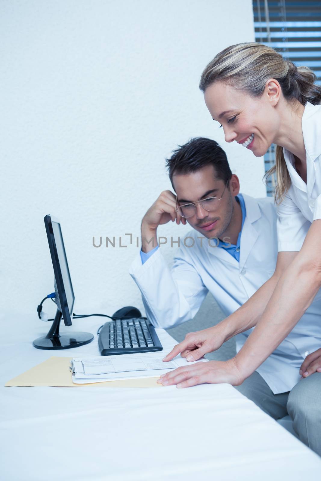 Smiling male and female dentists using computer