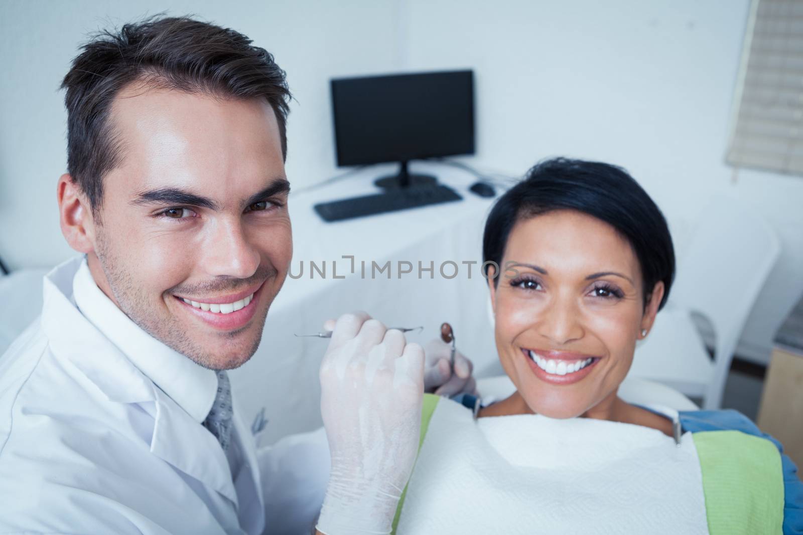 Male dentist examining womans teeth in the dentists chair